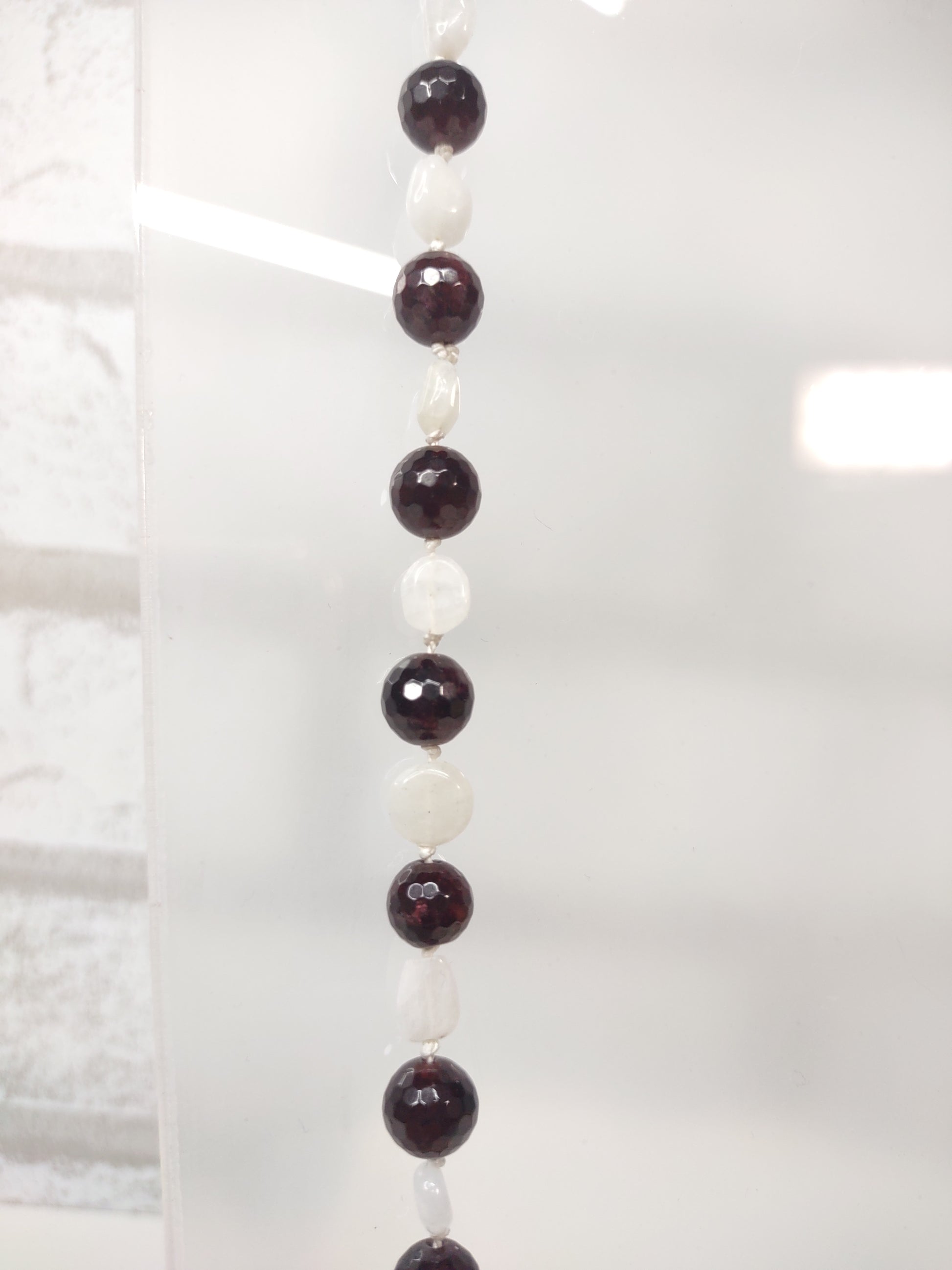 Large Faceted Garnet Beads and Moonstone nugget beads strung on 100% silk cord hand-knotted to separate each bead and finished with a stainless steel toggle. - Close up of beads