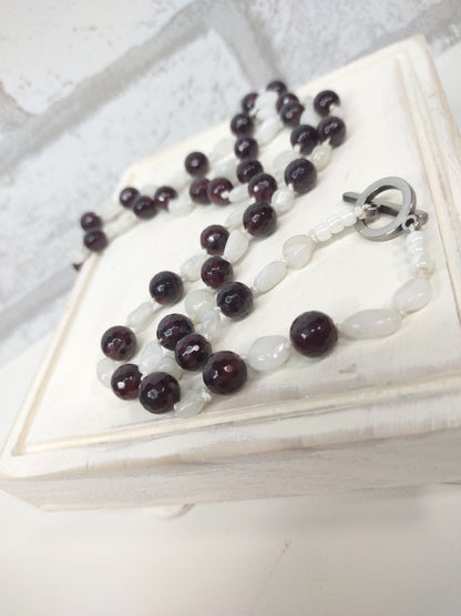 Large Faceted Garnet Beads and Moonstone nugget beads strung on 100% silk cord hand-knotted to separate each bead and finished with a stainless steel toggle. - laying down close up